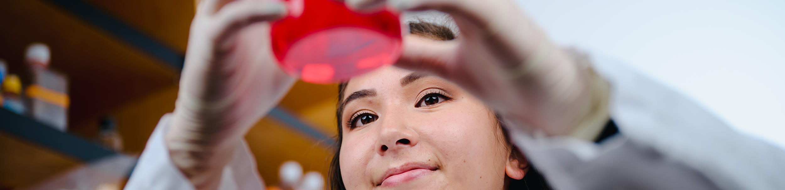 Researcher holding up a glass with red liquid