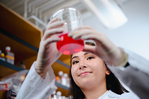 Researcher holding up a glass with red liquid